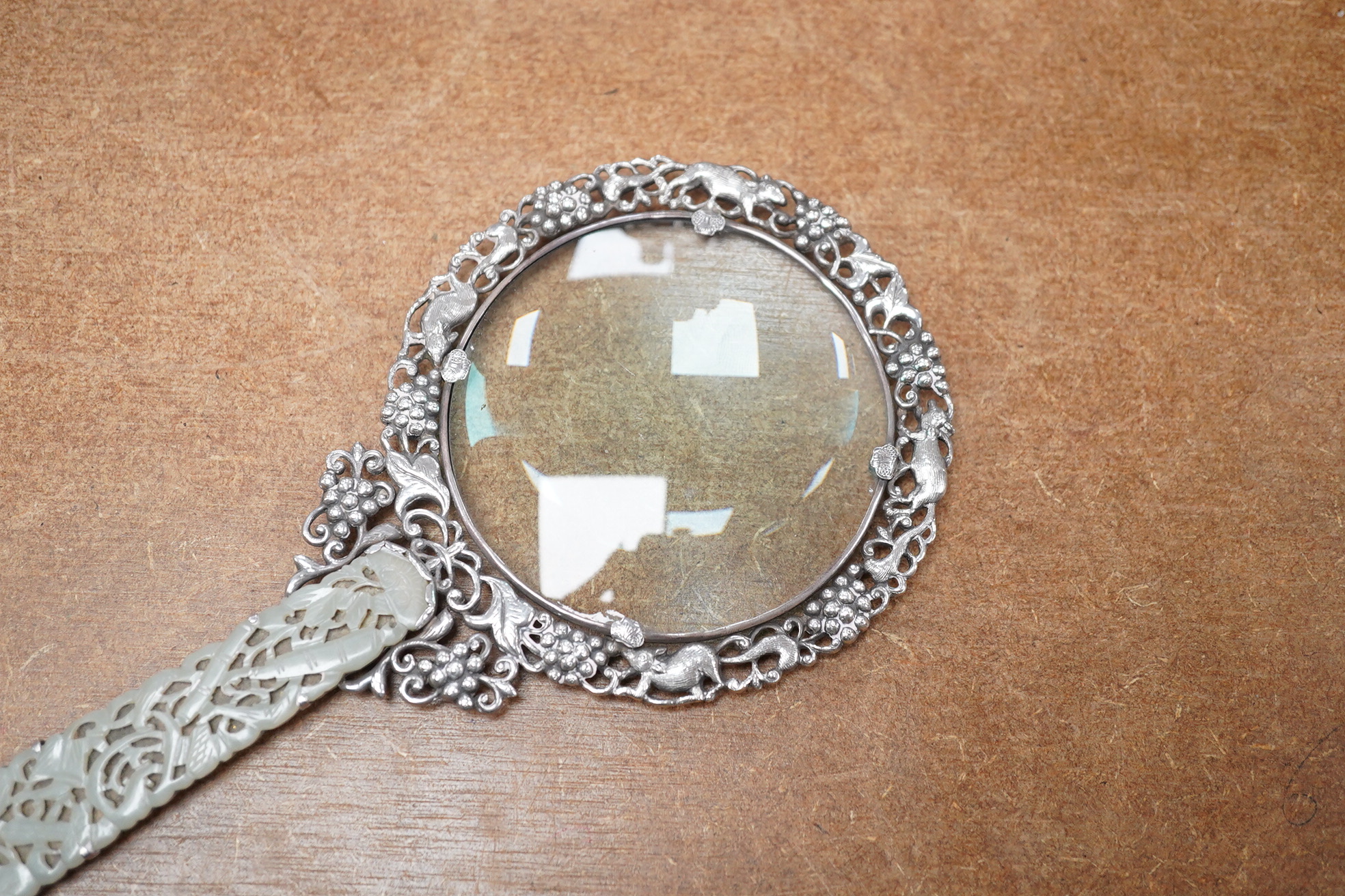 A Chinese white metal and pale celadon jade handled magnifying glass, early 20th century, stamped ‘SILVER’, 19cm long. Condition - good